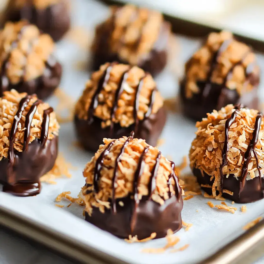 Rows of chocolate-dipped coconut candies on a tray, highlighted with chocolate drizzle.