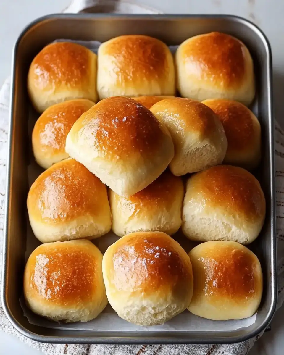 Golden rolls in a pan, one stacked on top of the rest.