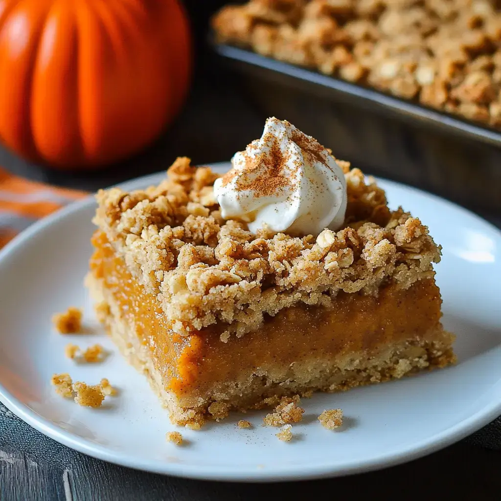 Pumpkin treat with whipped cream dusted with cinnamon, on a white plate, little pumpkin nearby for autumn touch.