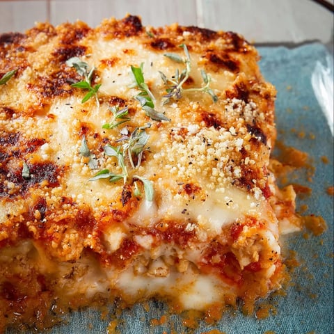 A slice of lasagna with cheese and herbs.