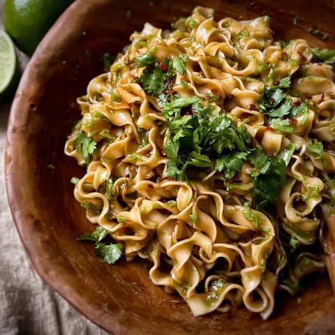 A bowl of noodles with vegetables and limes.